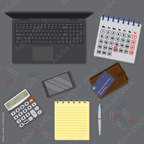 View of office drak desk background including laptop, digital devices, financial and business objects.