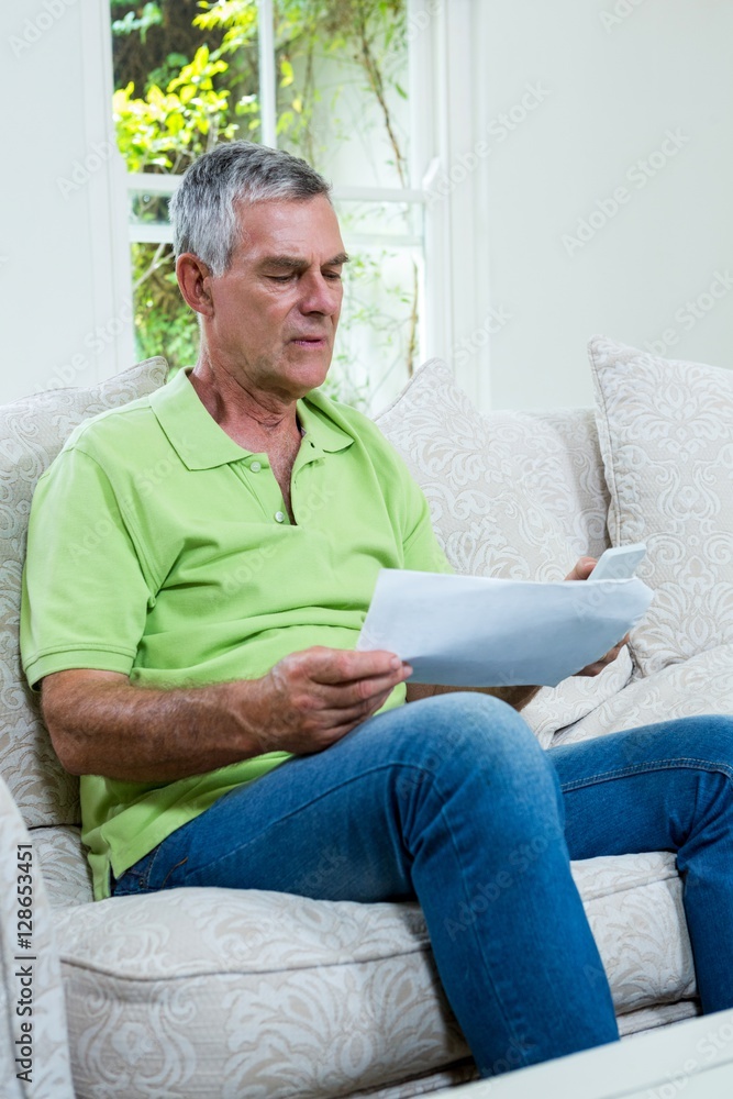 Worried senior man holding documents at home Worried senior man holding documents at home