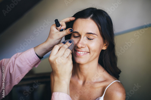 makeup artist doing makeup for beautiful and young girl