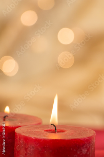 Lit red candles closeup and golden background with bokeh.