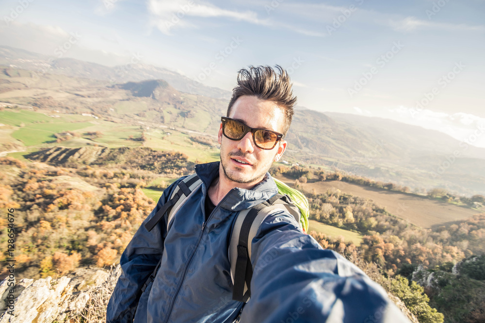 Handsome hiker taking a selfie on the top of a mountain. Concept about hiking, people, technology and lifestyle Handsome hiker taking a selfie on the top of a mountain. Concept about hiking, people, technology and lifestyle