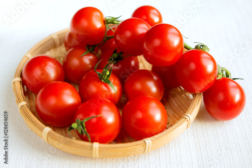 Cherry tomatoes in a small wicker basket on a white background