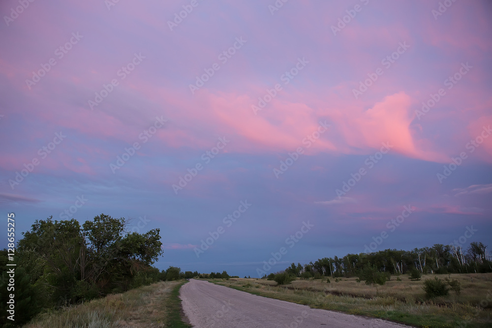sunset in cloudy sky over road