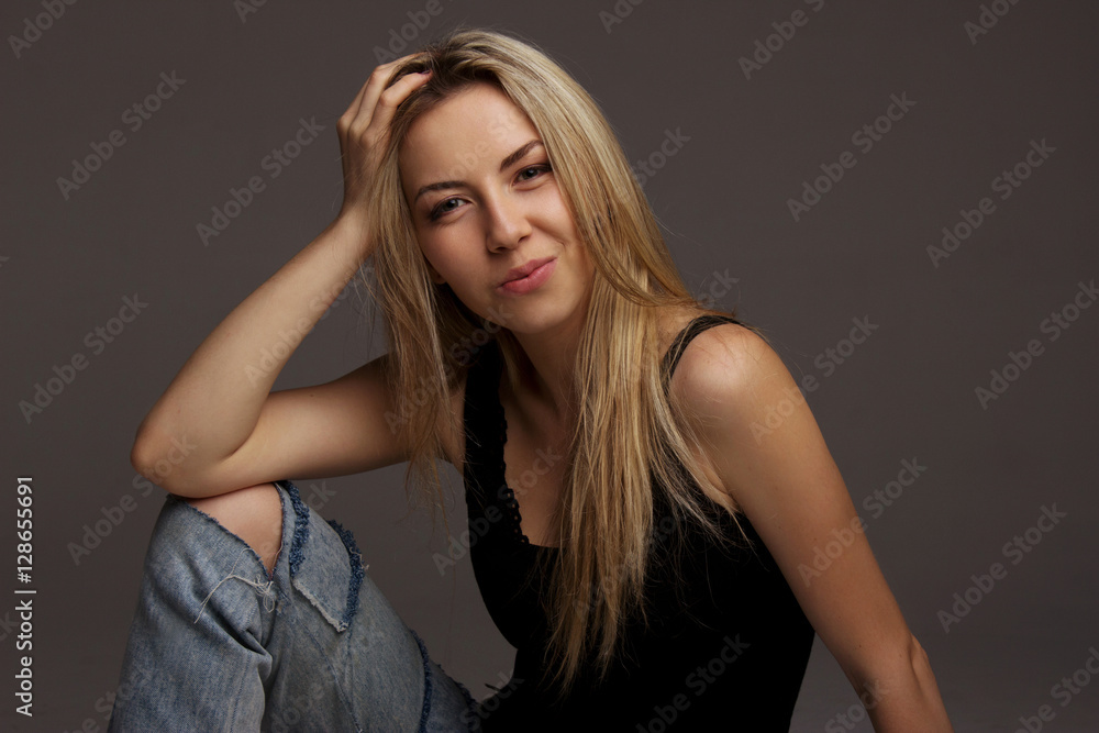 Beautiful young woman.Beauty portrait of young attractive blonde woman with long hair and natural makeup. Blonde woman sitting on the floor in the studio. Girl smiling to the camera. Model test