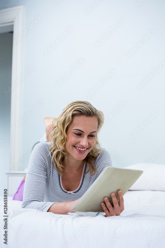 Smiling woman using digital tablet on bed Smiling woman using digital tablet on bed