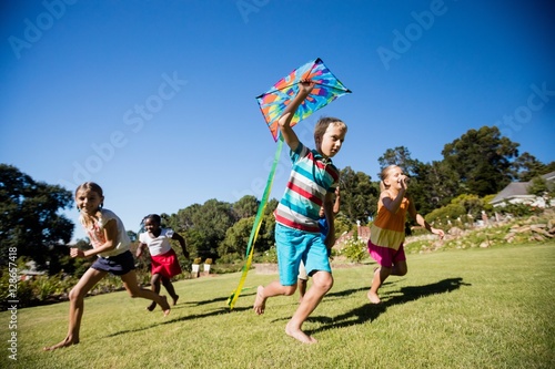 Kids playing together during a sunny day with a kite  © WavebreakMediaMicro