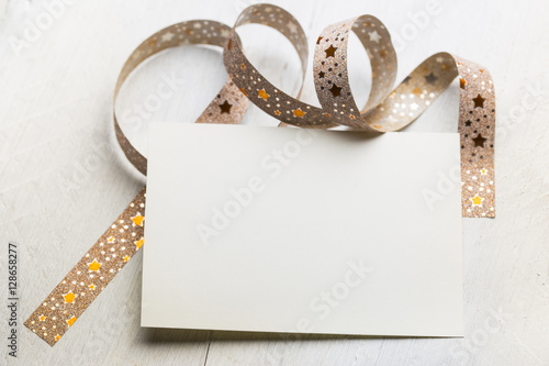 white greeting card and red ribbon on old wooden background