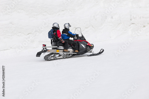Couple driving snowmobile in snowy field