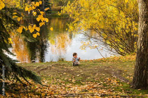 Baby boy holding an Autumn leaf in the park