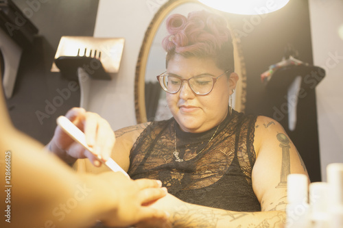 Beautician giving manicure service to customer in salon photo