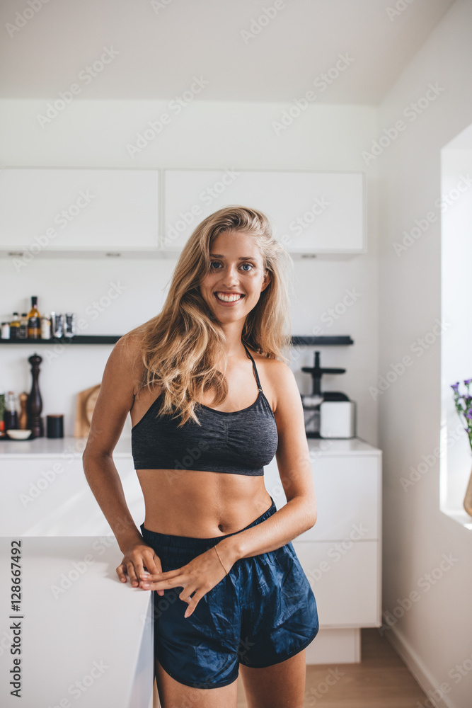Smiling young woman standing relaxed in kitchen Smiling young woman standing relaxed in kitchen