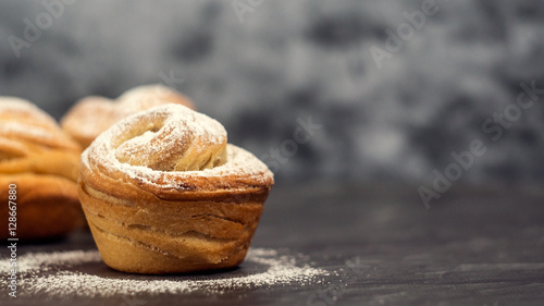 Homemade pastries cruffins, muffin with sugar powder, on dark background, selective focuse close up, copy space