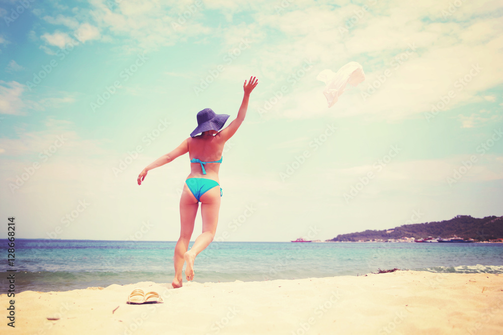 Woman in blue bikini throwing her hat on the beach Woman in blue bikini throwing her hat on the beach