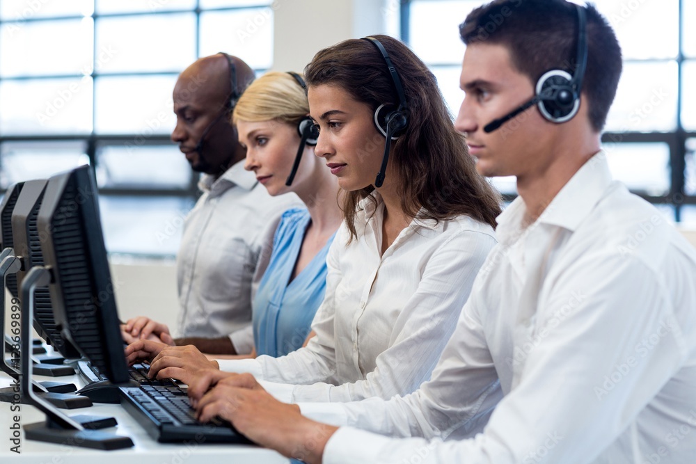 Team of colleagues working on computer with headset Team of colleagues working on computer with headset