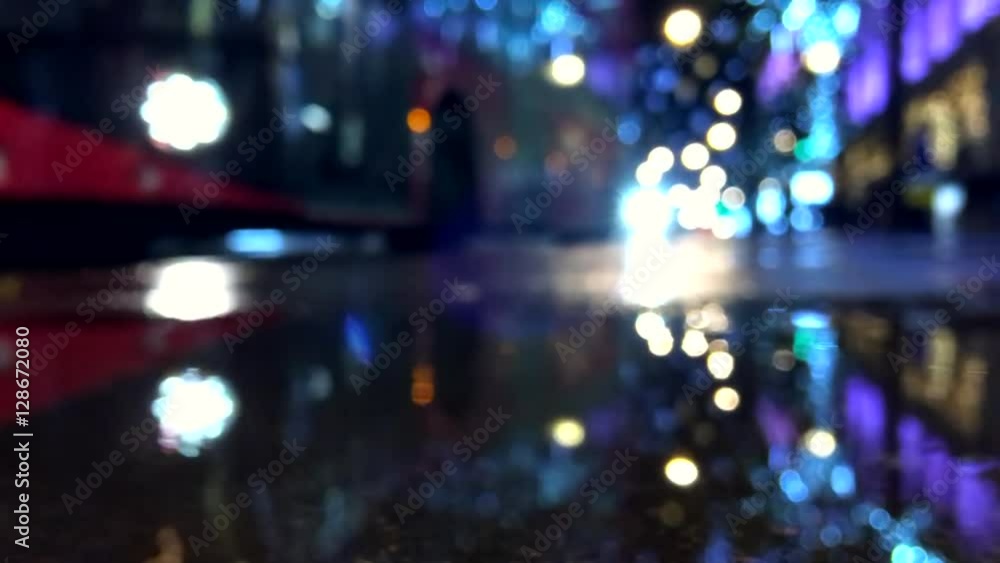 Defocus night view of holiday lights and city traffic reflecting in a rain puddle on the streets of London Defocus night view of holiday lights and city traffic reflecting in a rain puddle on the streets of London