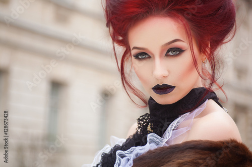 sexy woman with gothic makeup and red hair against old castle