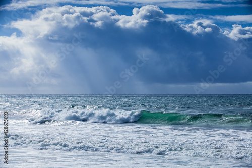 storm surf and rain clouds with rays of sunlight 