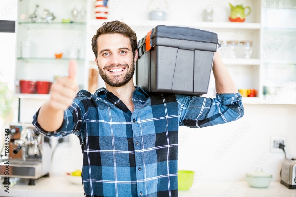 Man carrying tool box giving thumbs up