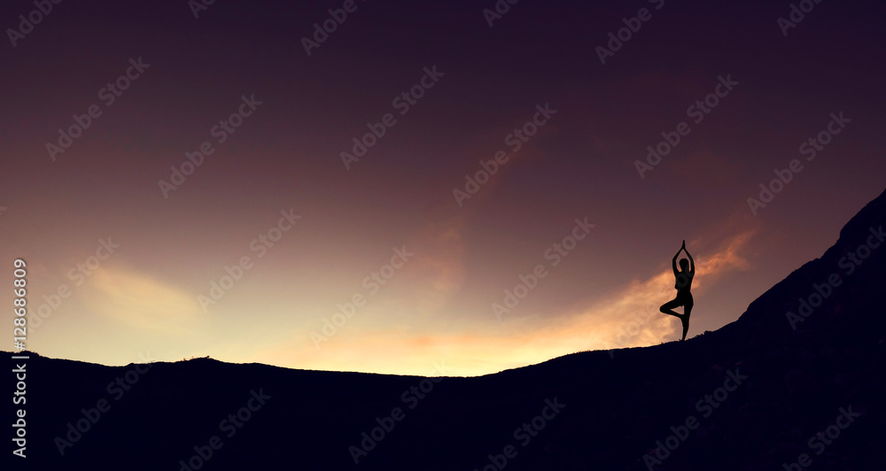 Silhouette mountain edge young woman practicing yoga on mountain in sunrise