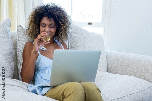 Woman having wine while using laptop