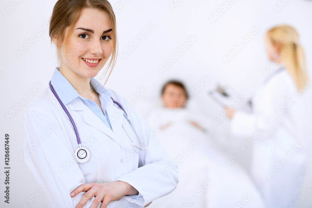 Female doctor smiling on the background with patient and his doctor Female doctor smiling on the background with patient and his doctor