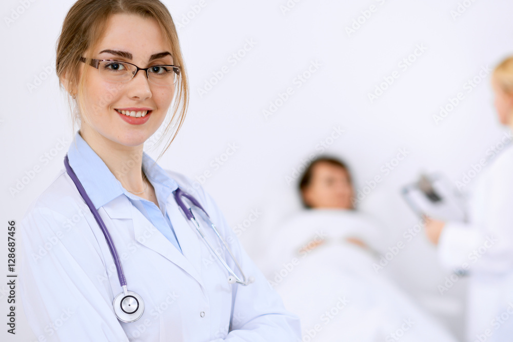 Female doctor smiling on the background with patient and his doctor Female doctor smiling on the background with patient and his doctor