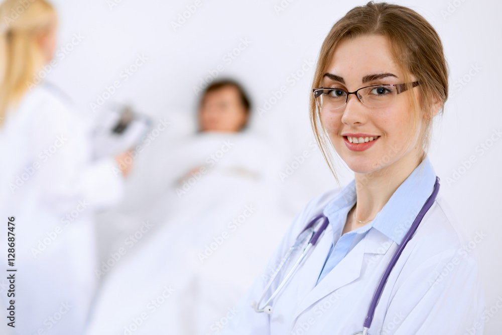 Female doctor smiling on the background with patient and his doctor Female doctor smiling on the background with patient and his doctor