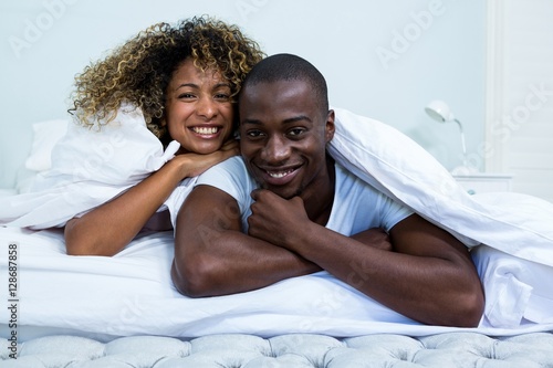 Portrait of happy couple embracing each other on bed