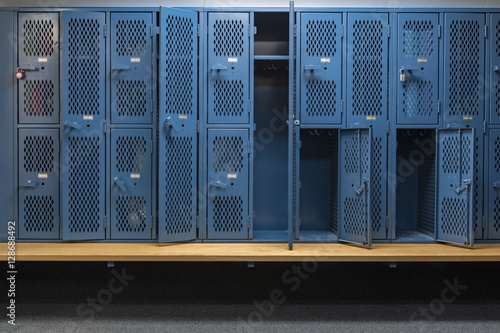 Fototapeta Blue metal cage lockers in a locker room with some doors open and some closed wi