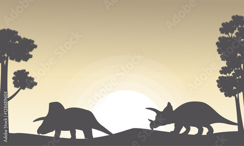 Silhouette of two triceratops on the hill scenery
