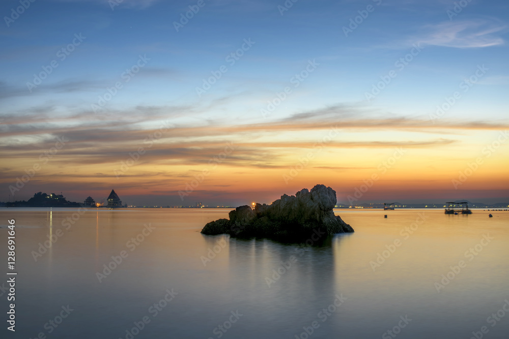 Single stone island in the sea beach with beautiful sunset