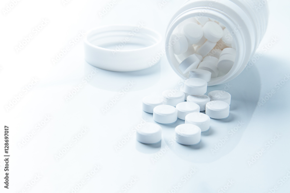 Pills spilling out of pill bottle and isolated on white. with co Pills spilling out of pill bottle and isolated on white. with co