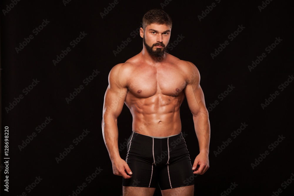 Strong Athletic Man Fitness Model Torso showing six pack abs. isolated on black background with copyspace