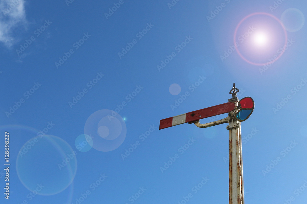 red and white lamplight semaphore signal in blue sky with lens flare red and white lamplight semaphore signal in blue sky with lens flare