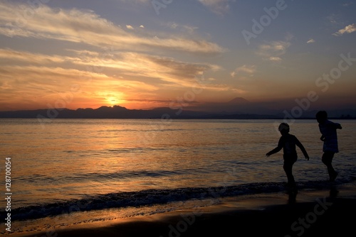 夕焼けの浜辺で遊ぶ子供たち