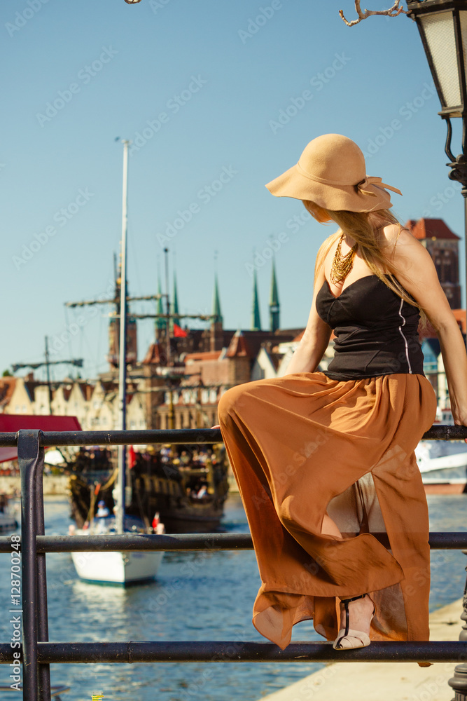 Sitting woman wearing big sun hat and elegant dress