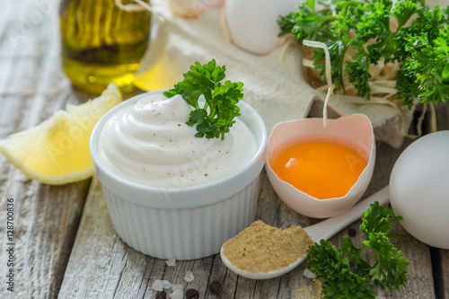 Mayonnaise sauce and ingredients on wood background