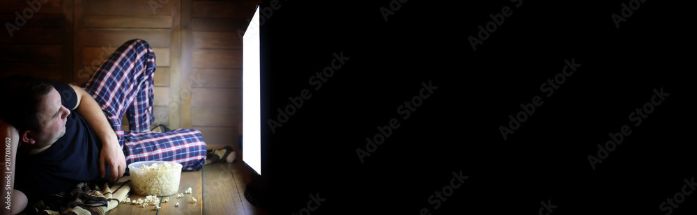 Naklejka premium man watching television at home on the floor