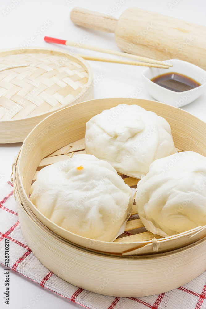Steamed pork buns (chinese dim sum) in bamboo basket, serve with chopsticks and napkin on a white background, Closed up Steamed pork buns (chinese dim sum) in bamboo basket, serve with chopsticks and napkin on a white background, Closed up