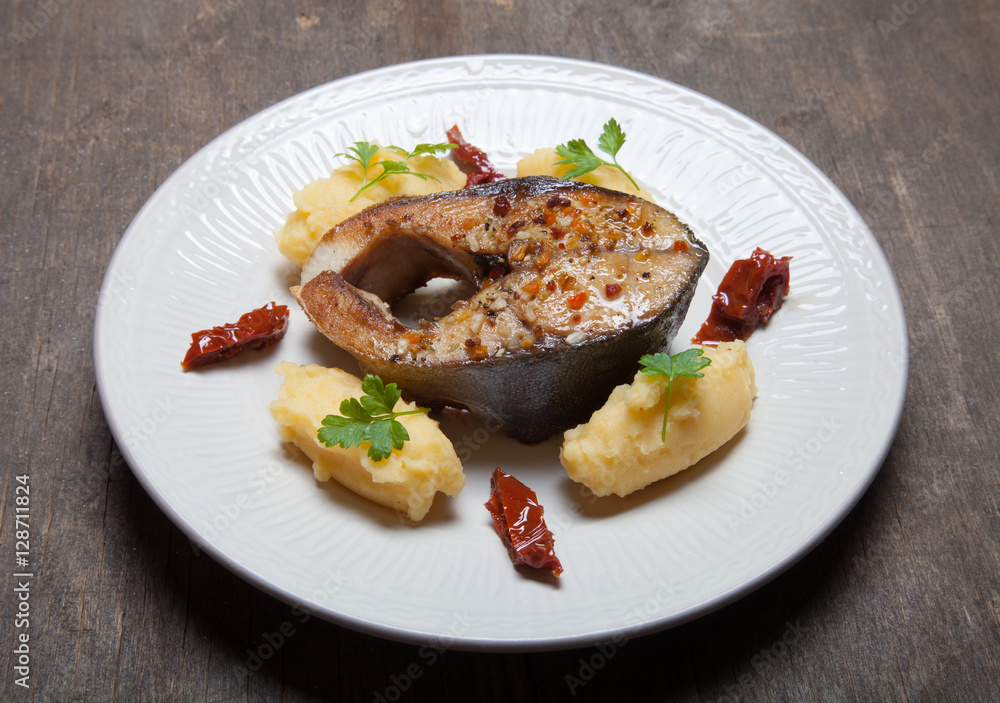 Fried tuna fish with mashed potato, dried tomato and parsley on