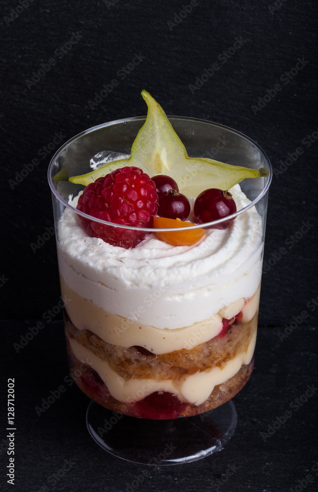 Small snacks trifle with fruits and cream in plastic glass on a Small snacks trifle with fruits and cream in plastic glass on a