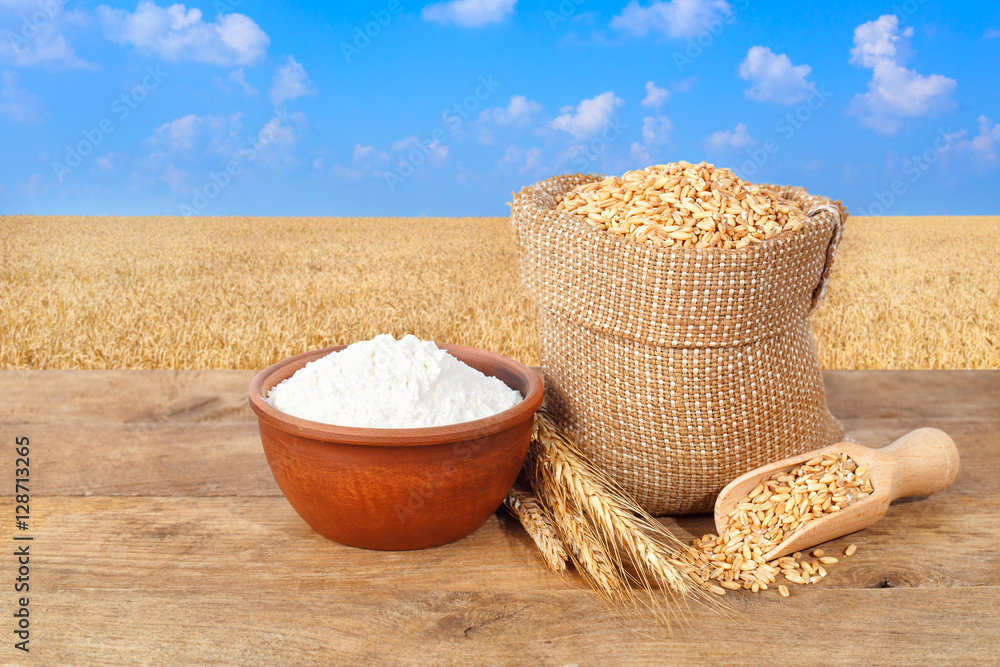 wheat grains and flour on wheat field background