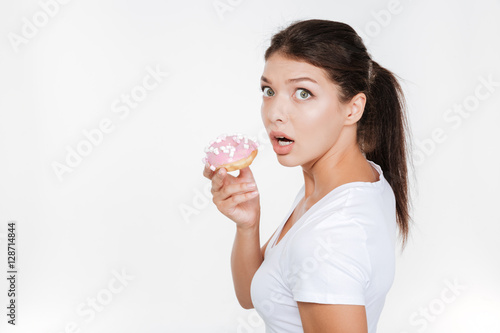 Confused diet young woman holding tasty donut