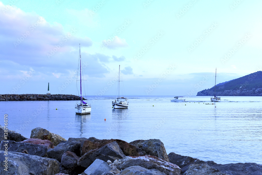 Harbor scene or sea scene with anchored boats at blue hour.