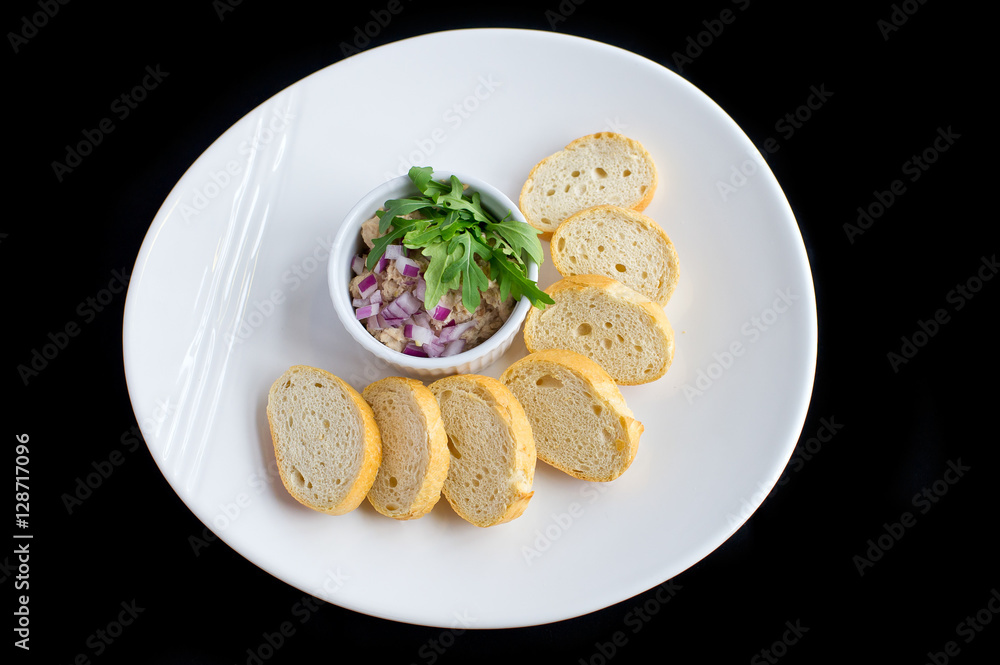 tuna salad with onions, vegetables and toasted bread in white plate and black background