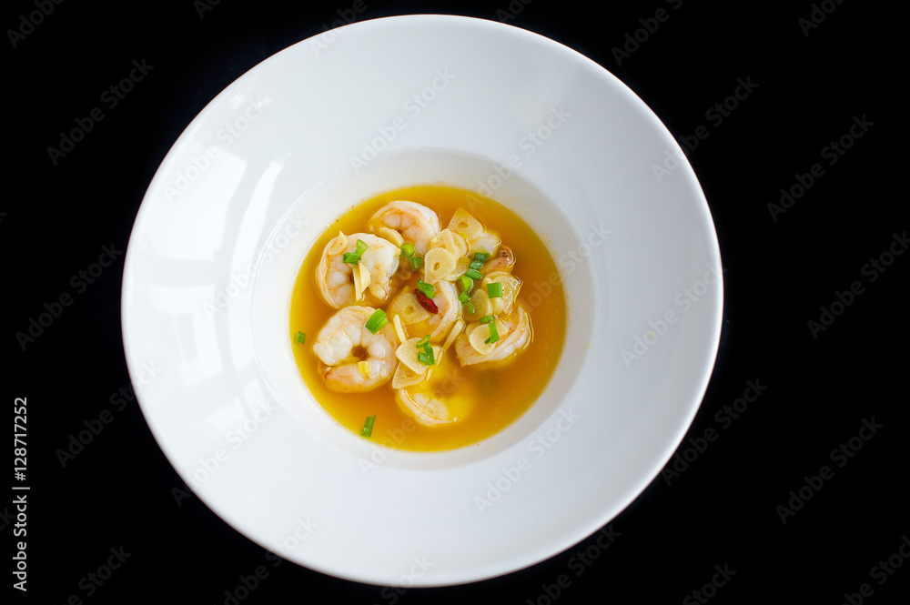 soup with shrimps and vegetables in white plate and black background soup with shrimps and vegetables in white plate and black background