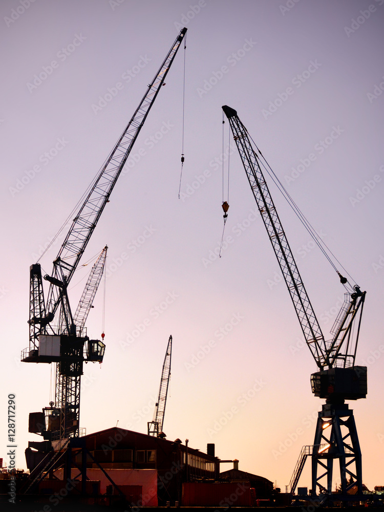 Harbor cranes in the sunset or sundown, freight shipping or container harbor  scene.