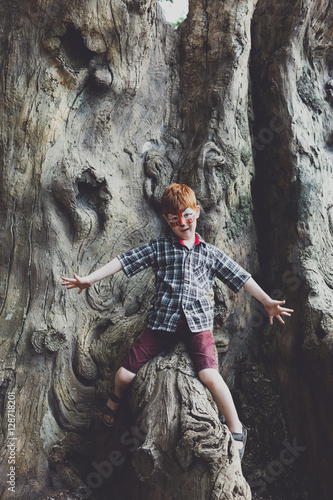 Fototapeta Naklejka Na Ścianę i Meble -  Boy child outdoors climb tree with tiger face painting