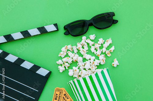 movie tickets, clapperboard, pop corn and 3d glasses in a green background.Flatlay