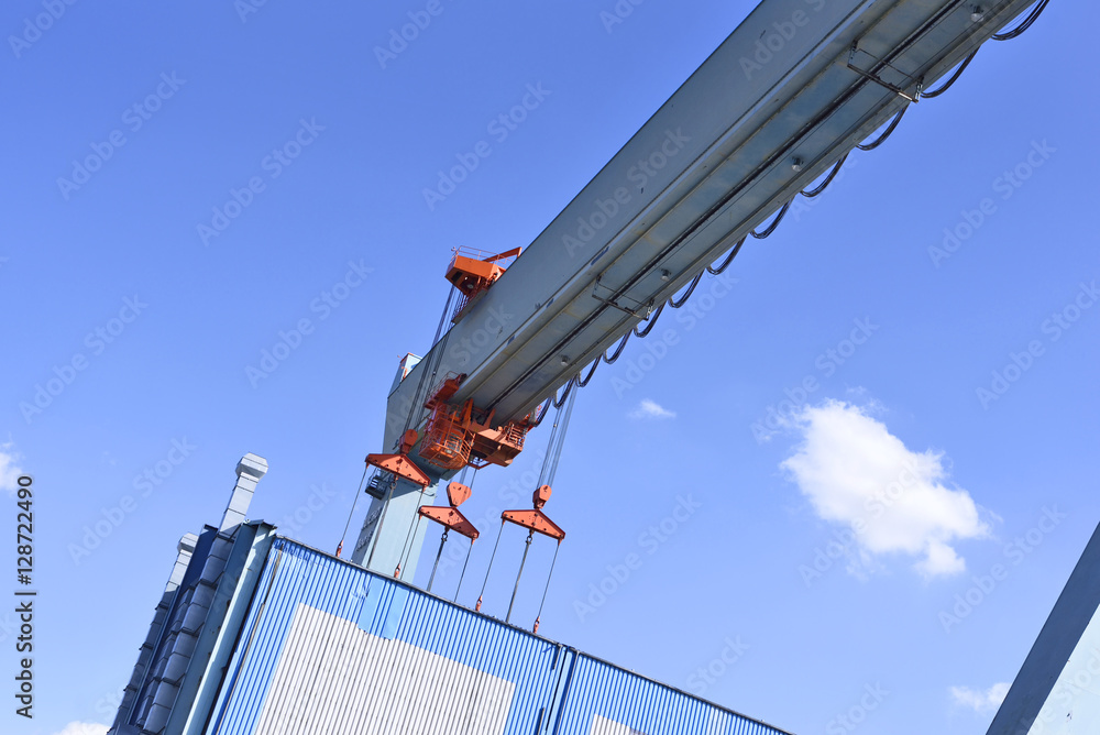 Container harbor, detail shot of a crane lifting up a cargo container.